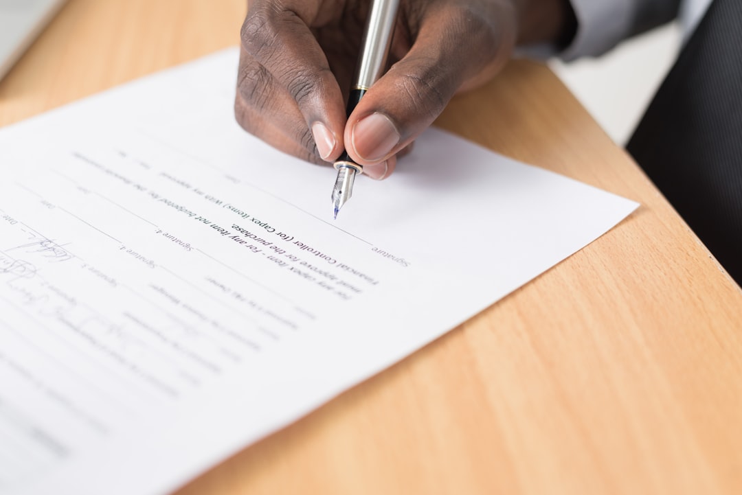 Person schreibt mit Stift die Kündigung des Mietvertrages auf weißem Papier
