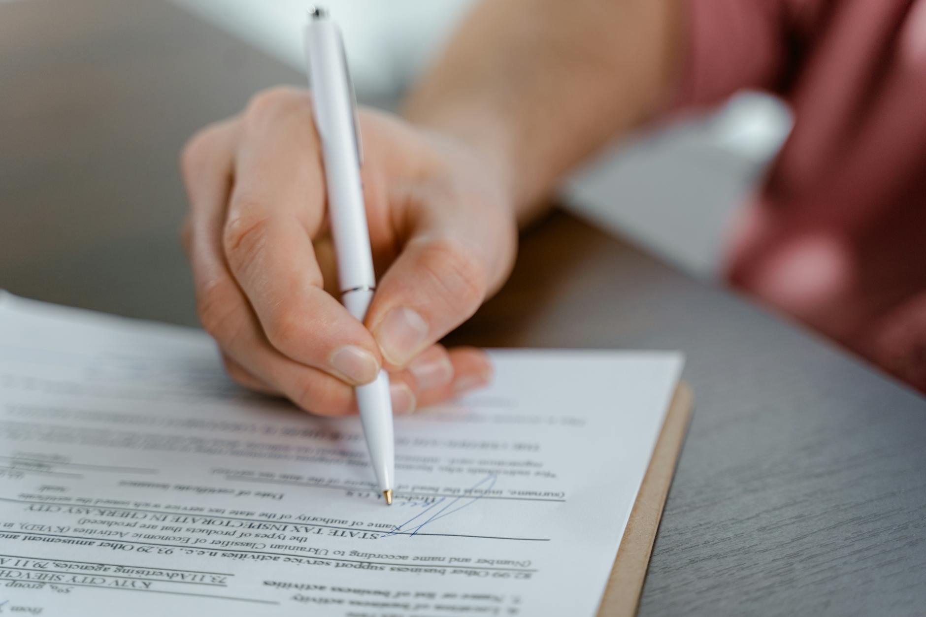 Hand unterschreibt mit Kugelschreiber ein Dokument – schriftliche Einwilligung ist bei Personenfotos im Rahmen der DSGVO der einzig sichere Weg